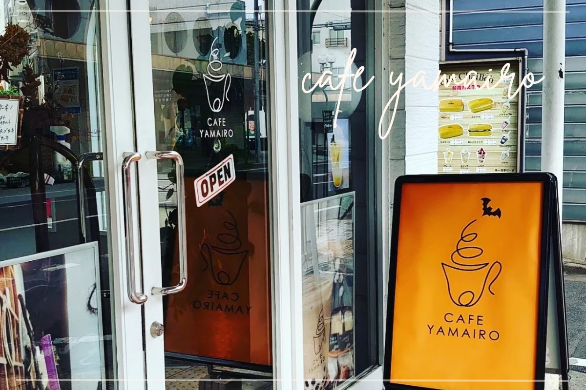桐生市にあるカフェ「CAFE YAMAIRO」の入口外観。オレンジ色の看板とガラス扉が目印。